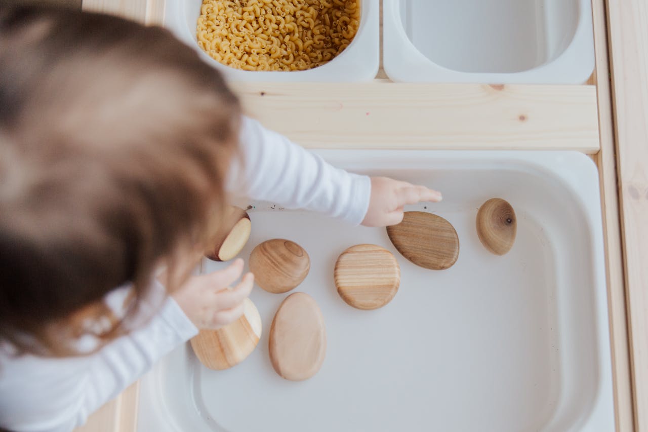 client-satisfaction-img A toddler playing with wooden stones in a Montessori educational setup, promoting motor skills development.